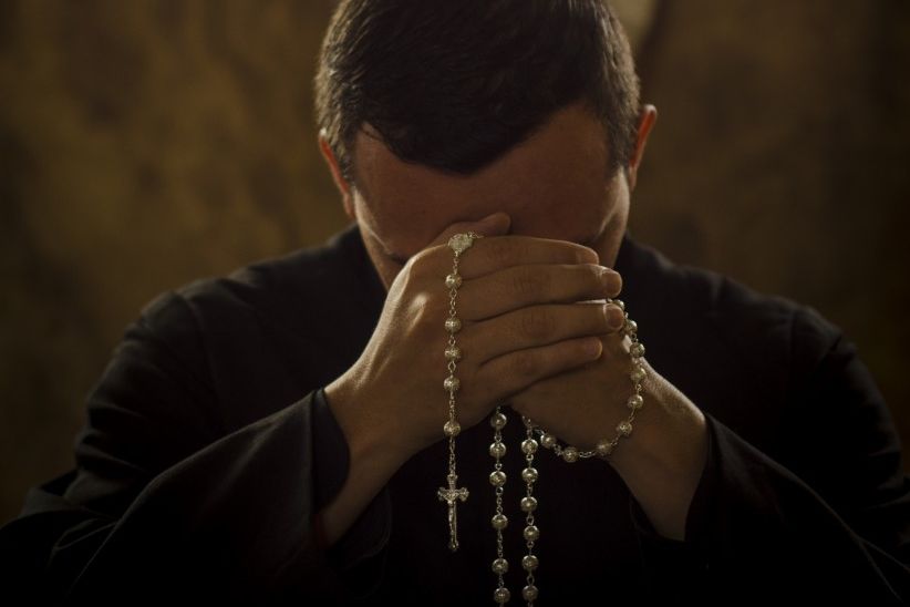 priest praying stock photo rosary