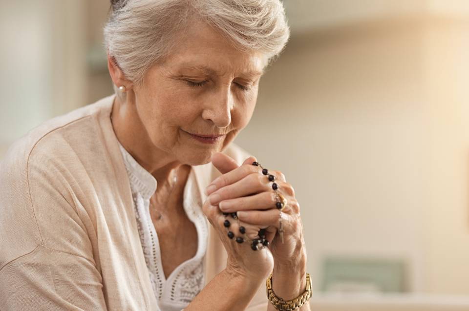 Elderly woman praying the rosary stock