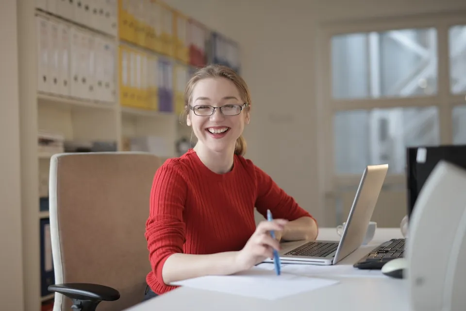 Stock photo of smiling woman in an office from pexels Andrea Piacquadio