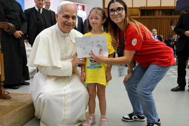 Pope Leo XIV bends down to take a photo with a girl taking part in the Vatican summer camp (@Vatican Media)