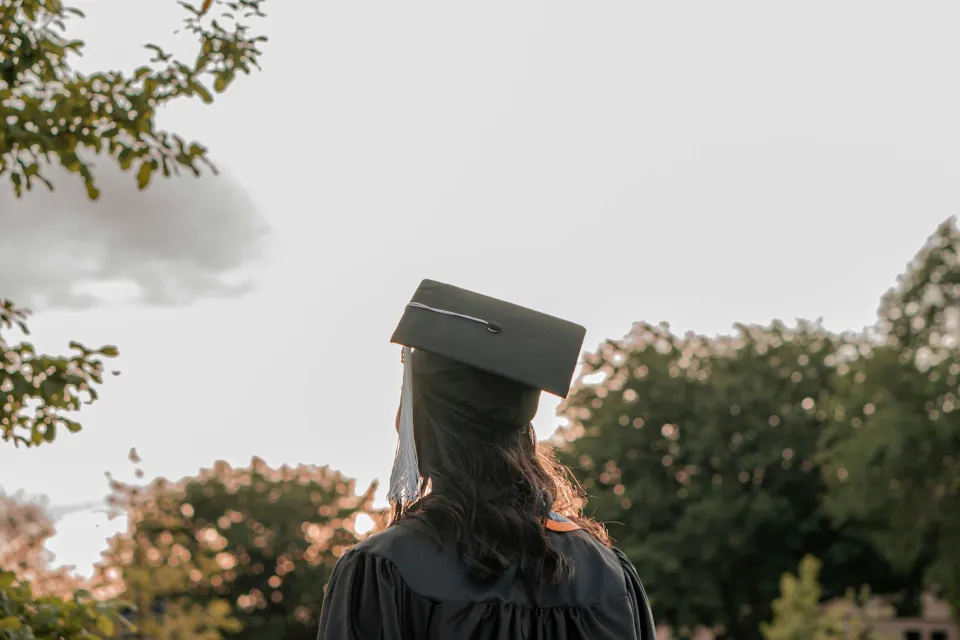 stock photo of woman wearing graduation cap and gown by Rebeca Alvidrez on Unsplash
