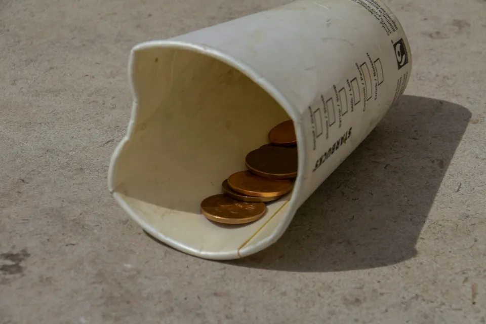stock Photo of poverty begging cup with coins of homeless by Nick Fewings on Unsplash